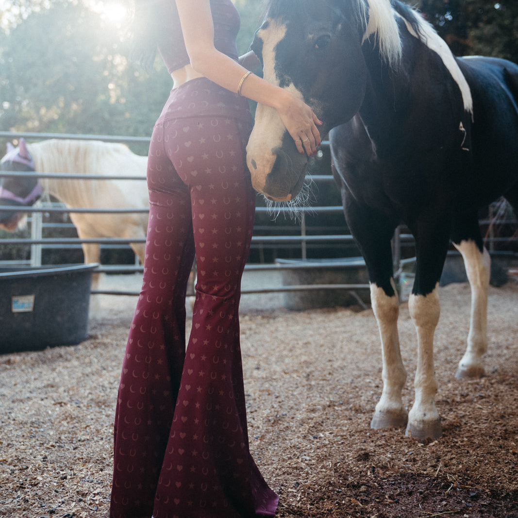 Back view of burgundy bell-bottom leggings with a small celestial pattern