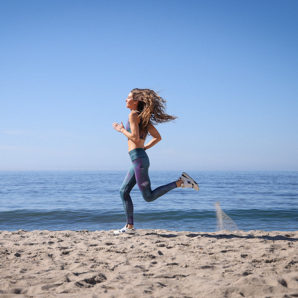 Woman running on a sandy beach with ocean and clear blue sky in the background